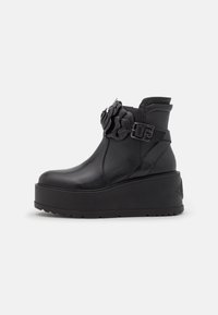 Czarne skórzane botki na kostkę z grubą platformą, z dekoracyjnym kwiatowym akcentem i zapięciem po boku.