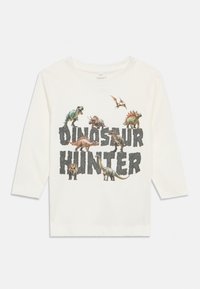 Λευκό μακρυμάνικο T-shirt με γραφικό δεινοσαύρου και κείμενο "Κυνηγός Δεινοσαύρων". Μαλακό βαμβακερό ύφασμα με λαιμόκοψη στρογγυλή.