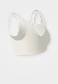 Brassière desport off-white sem costuras, com alças largas e textura canelada, projetada para conforto e suporte.
