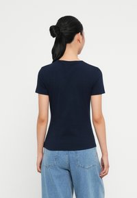 Tricou bleumarin cu mânecă scurtă, realizat din bumbac moale, ajustat la talie, cu un decolteu rotund și o textură netedă.