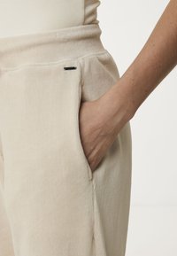 Beige corduroy broek met een ribbelstructuur; voorzien van een ingezette zak en een zwart label op de tailleband. Ontworpen met een losse pasvorm.