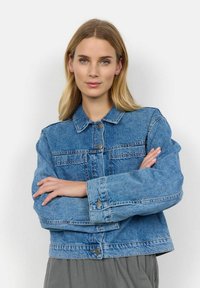 Denim jakna u svijetloplavoj boji, sa prednjim otvorom na dugmad, dva džepa na prsima i širokim rukavima. Tekstura izgleda čvrsto s vidljivim šavovima.