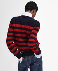 Gestreifter Pullover in Rot und Marineblau mit einem gerippten Saum und Bündchen. Ein weißer Kragen blitzt unter dem Pullover hervor. Getragen mit blauen Jeans.