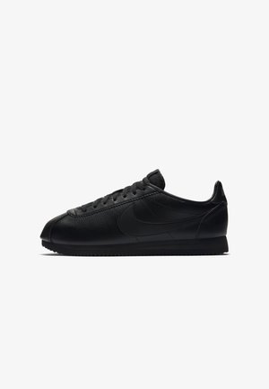 Czarny skórzany niski sneaker z czarnymi sznurowadłami i czarnym logo Nike Swoosh po boku, przedstawiony na białym tle.