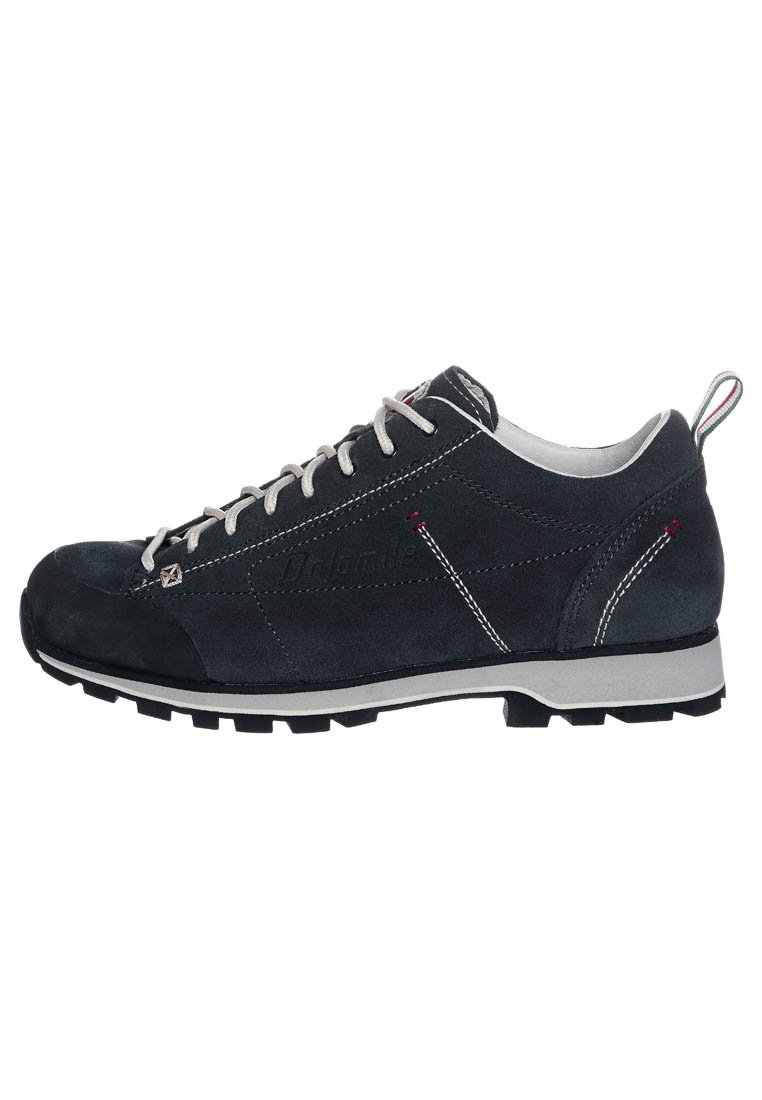 Chaussure de sport en suede noir avec un laçage, dotée d'une semelle en caoutchouc grise, de coutures claires et d'un petit accent rouge et blanc au niveau du talon.