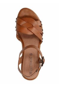 Brown leather sandal with woven strap design, ankle buckle, and circular studs. Smooth texture with a flat sole and cushioned insole.
