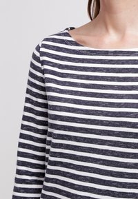 Chemise à manches longues à rayures navy et blanches en tissu doux, dotée d'un large col et d'une légère texture.