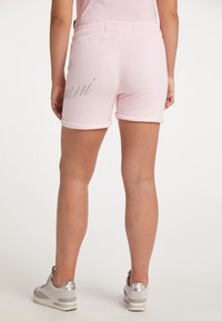 Helle rosa Shorts mit umgeschlagenem Saum und grauem Logo-Detail auf der Rückseite. Hergestellt aus weichem Material, mit einem elastischen Bund.