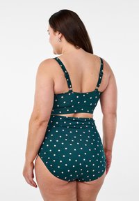 Tvådelad baddräkt med en teal-bas och rosa prickar, justerbara band och högmidjad design. Slät textur.