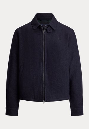 Veste zippée bleu marine foncé avec col et poches latérales, fabriquée en tissu texturé, présentée sur un fond uni.