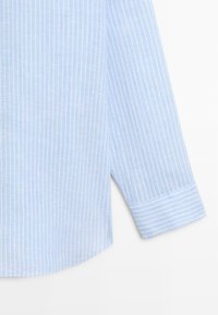 Hellblauer Hemdsärmel mit weißen vertikalen Streifen und einer Manschette mit horizontalem Streifenmuster, dargestellt auf weißem Hintergrund.