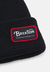 Berretto nero in maglia con tessuto testurizzato. Presenta una toppa rettangolare con il marchio "Brixton" in bianco su sfondo nero, contornata di rosso.