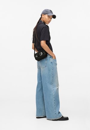 Černé tričko, světle modré široké džíny s děravým detailem, šedá čepice, černá crossbody taška se stříbrným kováním, černé boty.
