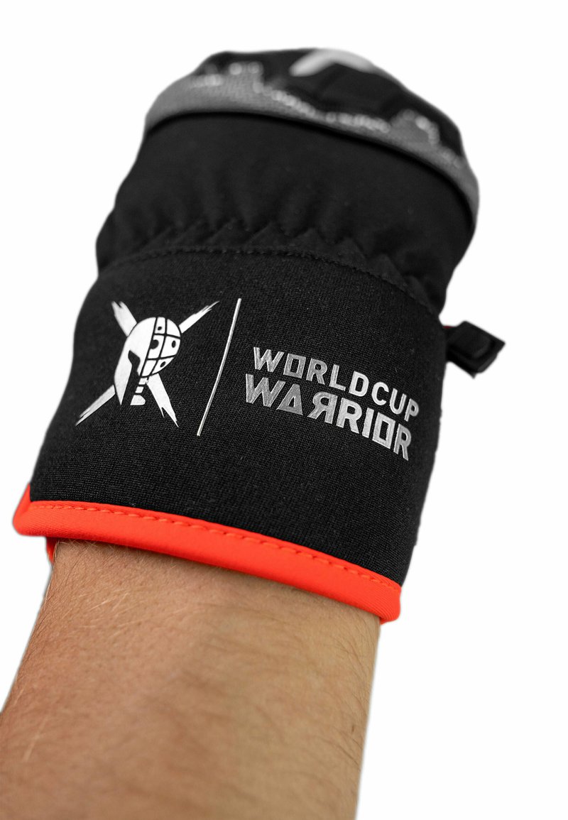 Zwarte handschoen met een oranje rand, voorzien van een logo en de tekst "WORLD CUP WARRIOR" in het grijs. Het ontwerp bevat een gestikte patroon bij de pols.