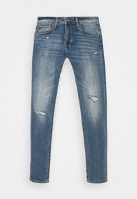 Jeans de denim azul de corte slim, com patches desgastados, lavagem desbotada, cinco bolsos, rebites de cobre e um cós padrão.