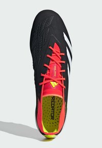Scarpa da calcio nera con accenti rossi, tomaia testurizzata, tre strisce bianche e suola gialla brillante. Presenta lacci prominenti e colletto imbottito.