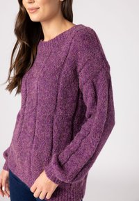 Lila gestrickter Pullover mit gerippter Textur, rundem Halsausschnitt und langen Ärmeln. Weiches Material mit einem gemütlichen Erscheinungsbild.