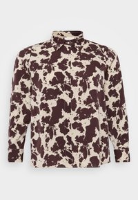 Camicia a maniche lunghe con colletto, di base beige e un distintivo motivo in pelle di mucca marrone scuro, con dettagli a bottoni e un fit rilassato.