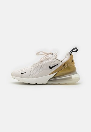 Beżowo-brązowy but sportowy Nike Air Max 270 z czarnymi logo Swoosh, siateczkową cholewką, piankową podeszwą środkową i widoczną poduszką powietrzną na pięcie na białym tle.