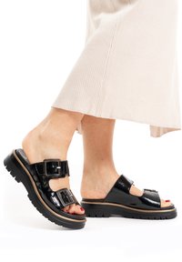 Black patent leather sandals with double buckle straps and a chunky rubber sole. Features an open toe design and a slight heel.