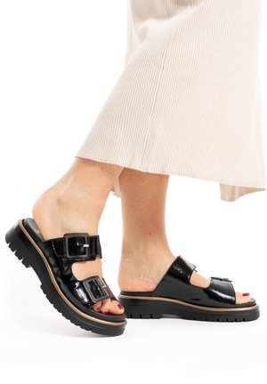 Black patent leather sandals with double buckle straps and a chunky rubber sole. Features an open toe design and a slight heel.