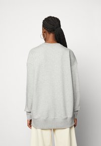 Gray sweatshirt with a relaxed fit, rounded neckline, dropped shoulders, and ribbed cuffs. Soft texture; plain design, no visible patterns.