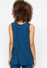 Mouwloze blauwe top met een relaxte pasvorm, een ronde halslijn en een iets langere achterkant. Soepele stoftextuur zonder zichtbare patronen of accenten.