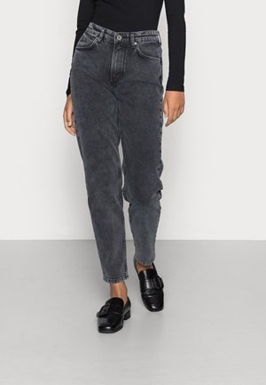 Jean taille haute, coupe droite en denim noir délavé avec une finition légèrement usée. Associé à des chaussures noires à enfiler avec une boucle.