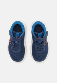Chaussures en mesh bleu marine avec doublure intérieure bleu vif, semelles blanches, design à lacets et sangle à boucle pour un maintien sécurisé.
