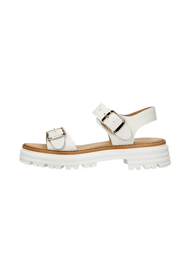 Des sandales blanches avec deux boucles réglables, une semelle texturée et une plateforme blanche épaisse et striée avec un coussin de pied marron.