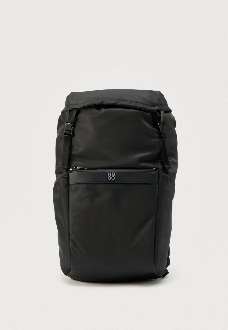 Μαύρο σακίδιο πλάτης από νάιλον με φερμουάρ στο μπροστινό τσαντάκι και ρυθμιζόμενους ιμάντες, με μικρό λογότυπο «HUGO» πάνω από το τσαντάκι.