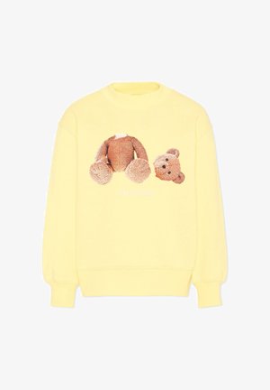 Sweat-shirt jaune avec un motif d'ours en peluche marron séparé en tête et corps sur le devant.