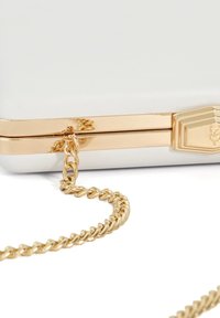 Witte rechthoekige clutch met gouden hardware, voorzien van een gevlochten kettingband en een gedetailleerde sluiting. Glad textuur, minimalistisch ontwerp.