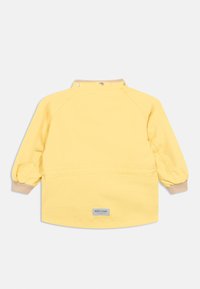 Rumena jakna z dolgimi, napihnjenimi rokavi, okrogel ovratnik in bež manšetami. Ima pritiskače in etiketo na zadnji strani. Gladek tekstura.