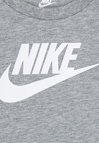 Γκρι βαμβακερό T-shirt με μεγάλο λευκό λογότυπο "NIKE" και σχέδιο swoosh. Ριχτή στρογγυλή λαιμόκοψη και απαλό υλικό.