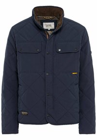 Marineblaue gequiltete Jacke mit zwei Brusttaschen, Druckknopfverschlüssen und einem braunen Cordkragen. Verfügt über einen gelben Akzent an der Seite.