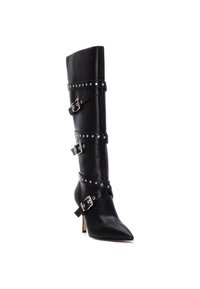 Botín de cuero negro hasta la rodilla con punta afilada, correas adornadas con clavos plateados y hebillas. Presenta un pequeño tacón y una textura suave.