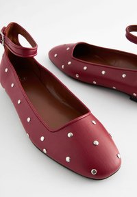 Burgundy læderballet flats med runde tæer, åben hæl, ankelrem og sølvnitter jævnt fordelt over overfladen.