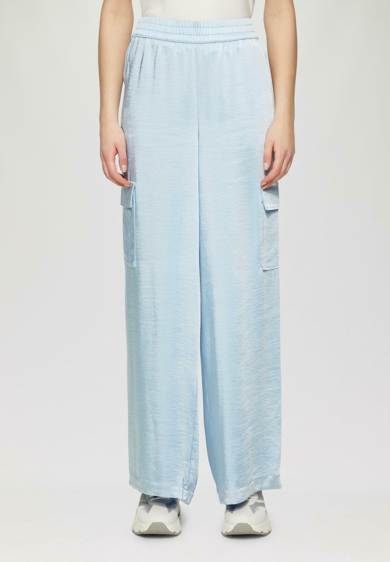 Hellblaue, weit geschnittene Hose aus einem weichen, strukturierten Stoff. Mit einem elastischen Bund und zwei Cargo-Taschen an den Seiten.