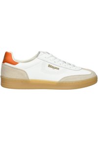 Bílé tenisky s béžovými semišovými akcenty, oranžovou patní částí, zlatým logem a perforovanými bočními detaily. Gumová podrážka. Šněrovací design.