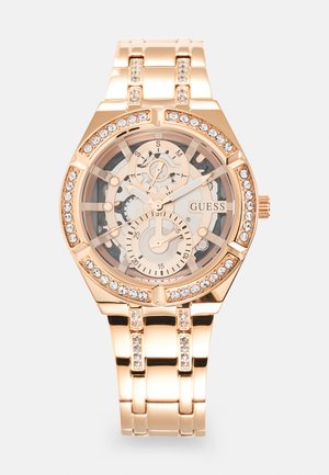 Orologio in oro rosa con quadrante trasparente, caratterizzato da ingranaggi intricati, accenti argento e cristalli scintillanti attorno alla lunetta e ai link del bracciale.