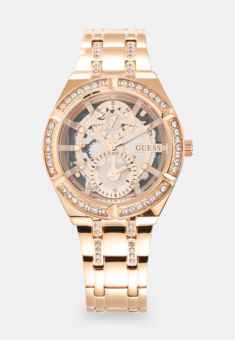 Rose gold watch with a transparent dial, featuring intricate gears, silver accents, and sparkling crystals around the bezel and bracelet links.