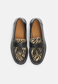 Black leather loafers with a zebra-patterned textile front, featuring tassel accents. Smooth finish and rounded toe design.