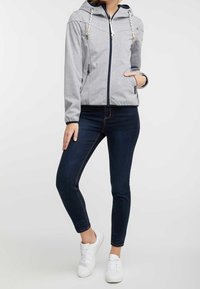 Šedá mikina na zip s kapucí, která má kontrastní námořnické lemování a dekorativní šňůrky. Kombinovaná s tmavými skinny džínami a bílými teniskami.