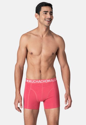 Red cotton boxer shorts featuring a white elastic waistband with "MUCHACHOMALO" text. Designed for a fitted style and comfort.