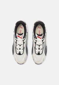 Sportieve sneakers met een witte mesh bovenkant, zwarte accenten, een rood logo, grijze zijpanelen en witte veters. Tekst "Ortholite" zichtbaar binnenin.
