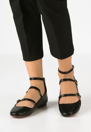 Czarne skórzane baleriny z wieloma cienkimi paskami, prostokątnym kształtem nosa i małymi klamrami. Gładka faktura z delikatnym połyskiem.