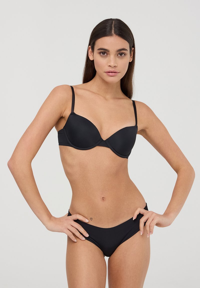Set di reggiseno e bikini neri realizzati in tessuto morbido. Il reggiseno presenta un design sagomato con spalline regolabili. Il bikini ha un taglio a vita bassa.
