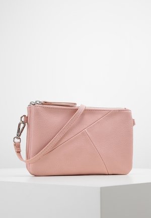 Petit sac à main poignet rose pâle en cuir texturé, avec couture diagonale, fermeture éclair et bandoulière amovible sur une surface blanche.