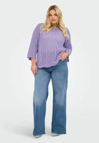 Lavendel gebreide trui met een ronde halslijn en losse 3/4 mouwen, gecombineerd met lichtblauwe brede jeans en mintgroene schoenen.